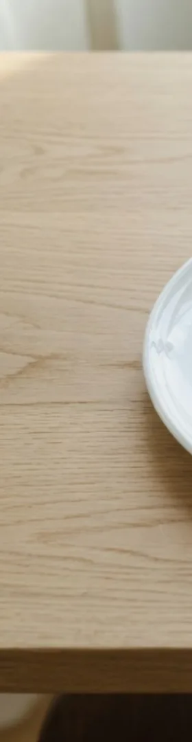 The left edge of the center crop, bare table and a sliver of the plate, with no cup